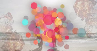 Sahilde yürüyen insanların siluetlerini kaplayan renkli dairelerin animasyonu. canlı, soyut, hareket, günbatımı