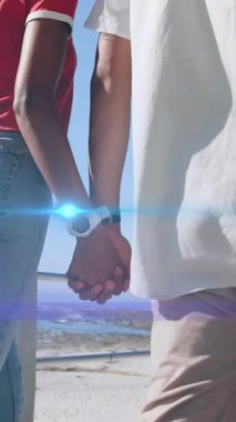 Sahilde el ele tutuşarak yürüyen çiftin ortasında hareket eden ışığın animasyonu. Tatiller, aktif yaşam tarzı ve pozitiflik kavramı dijital olarak oluşturulmuş animasyon.