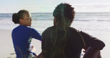 Sahilde oturmuş, iki insan okyanus manzaralı güneşin altında dinleniyor. Tatil, rahatlama, güneş ışığı, boş zaman, deniz manzarası, ufuk.