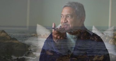 Telefonda konuşan, kayalık okyanus kıyısında duran yaşlı bir adam. Son sınıf, sohbet, deniz, sahil, doğa, tefekkür