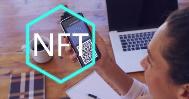 Masanın üzerinde NFT metin animasyonu olan akıllı telefondan QR kodunu tarıyorum. Teknoloji, dijital, engelleme zinciri, yenilik, şifreleme, etkileşim