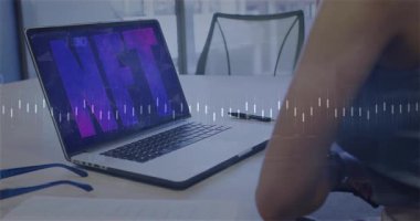 NFT metin animasyonu dizüstü bilgisayar ekranında ve finansal veri tabloları ofiste. Kripto para birimi, dijital sanat, engelleme zinciri, teknoloji, finans, yatırım