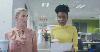 Elinde kahve fincanları ve gazeteler, ofiste dijital verilerin animasyonunu izleyen kadınlar. Teknoloji, takım çalışması, işbirliği, iş dünyası, çalışma alanı, beyin fırtınası