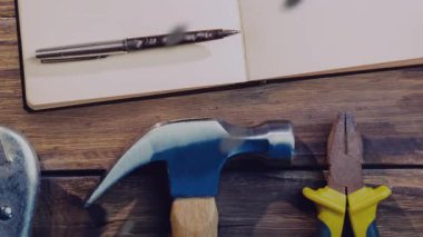 Tahta masa, çekiç ve kerpeten yanında defter ve kalem animasyon için. Aletler, atölyeler, el sanatları, marangozluk, inşaat, DIY