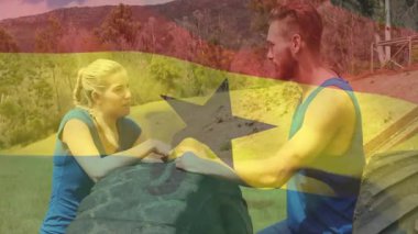 Spor giysilerinde, iki kişi Gana bayrağı animasyonuyla büyük bir lastiğin üzerinden konuşuyor. Fitness, egzersiz, takım çalışması, güç, sohbet, animasyon