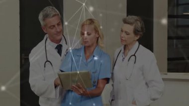 Doktorlar tablet üzerinde hasta verilerini ve ağ bağlantılarını tartışıyor. Sağlık, teknoloji, işbirliği, dijital, yenilik, iletişim