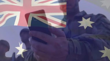 Arkaplanda Avustralya bayrağı animasyonu olan bir asker akıllı telefon kullanıyor. Askeri, teknoloji, vatanseverlik, iletişim, savunma, dijital
