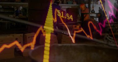 Değişen borsa grafiği analiz ediliyor, fabrikada çalışanlar animasyona odaklanıyor. Ekonomi, finans, eğilimler, iş, endüstri, imalat