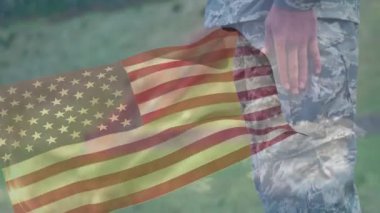 Dışarıda dikilen askeri üniformalı birinin üzerine Amerikan bayrağı sallıyor. Vatanseverlik, onur, asker, milli gurur, hizmet