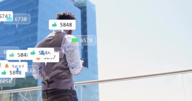 Balkonda duran adam, şehir manzarası üzerinde sosyal medya bildirimlerini canlandırıyor. Teknoloji, iletişim, dijital ağ, yaşam tarzı, gökdelen