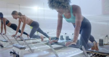 Reform makineleri üzerinde egzersiz yapan kadınlar animasyon için dijital arayüz kullanıyor. Egzersiz, fitness, pilates, teknoloji, spor, egzersiz