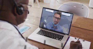 Ofis masasında dizüstü bilgisayarla iş arkadaşı, sağlık uzmanı ile görüntülü görüşme. Teletıp, sanal toplantı, video görüşmesi, uzaktan danışma, tele sağlık, online iletişim