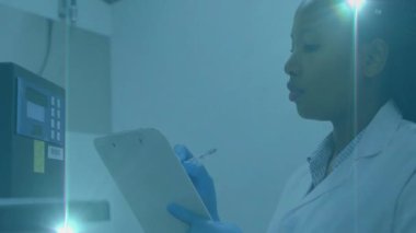 Laboratuvarda, eldivenli bilim adamı mavi ışık animasyonu altında notlar alıyor. Araştırma, deney, bilim, analiz, keşif, yenilik