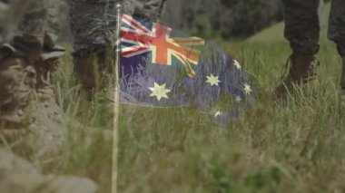 Askeri botlar çim tarlasında Avustralya bayrağına basıyor ve animasyon etkisi yapıyor. Vatanseverlik, saygısızlık, çatışma, protesto, milliyetçilik, sembolizm