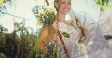 Güneşli bahçe ortamında elinde buket tutan gelin neşeyle dışarıda sallanıyor. Düğün, kutlama, mutluluk, çiçekler, gelin, gün ışığı