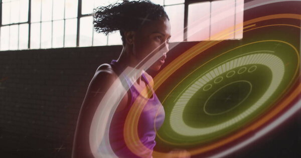 Изображение красочных кругов над женщиной, бегающей в заброшенном здании. Цифровой интерфейс глобальной концепции спорта и перформанса.