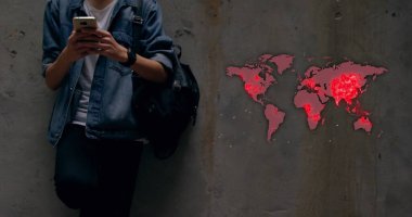 Genç adam dünya haritası ile akıllı telefonu kontrol ediyor. Salgın noktalarını vurguluyor. Teknoloji, bağlantı, küresel, salgın, iletişim, analiz