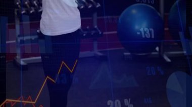 Spor salonunda, finansal veri işleme animasyon örtüsüyle egzersiz yapan bir kadın. Egzersiz, fitness, teknoloji, analiz, finans, sağlık