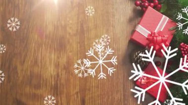 Kırmızı hediye kutuları ve ahşap arka planda kar taneleri animasyonu olan kozalaklar. Noel, tatil, şenlik, dekorasyon, kış, kutlama