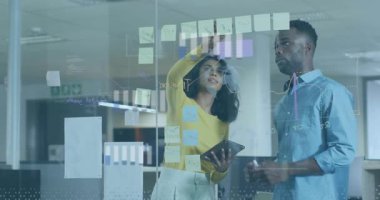 Projede işbirliği, ofiste dijital grafikler ve yapışkan notlar kullanan meslektaşlar. Takım çalışması, beyin fırtınası, yenilik, işbirliği, çalışma alanı, strateji