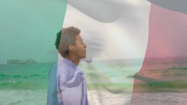 Sahilde duran, üzerinde İtalyan bayrağı olan adam, kıyı melteminin tadını çıkarıyor. Vatanseverlik, kıyı şeridi, rahatlama, erkek, seyahat, doğa