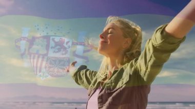 Güneşli havada, sahilde İspanyol bayrağı animasyon örtüsü olan bir kadın. tatil, güneş ışığı, yaz, seyahat, rahatlama, vatanseverlik