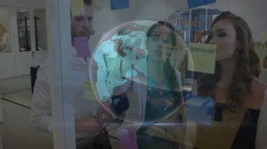 Modern ofiste, ekip beyin fırtınası için dijital küre kullanılıyor ve animasyon verileri üst üste getiriliyor. İşbirliği, yenilik, takım çalışması, teknoloji, iş dünyası, küresel