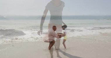 Kumsalda, baba onun neşeli gülümseyen yüzünün animasyonuyla çocuğunu kaldırıyordu. Aile, bağ, babalık, mutluluk, yaz, tatil