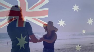 Kumsalda, kadın ve erkek Avustralya bayrağı taşıyor, gülümsüyor ve eğleniyorlar. Tatil, tatil, vatanseverlik, kutlama, sahil şeridi, çift