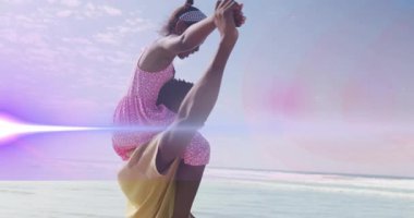 Plajda, pembe elbiseli çocuk animasyonla yetişkinlerin omuzlarında oynuyor. Tatil, kum, aile, eğlence, neşe, okyanus