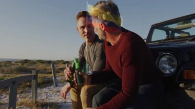 Plajda araçta oturan, iki adam içki içip birlikte rahatlıyor. Tatil, tatil, arkadaşlık, seyahat, günbatımı, yaz