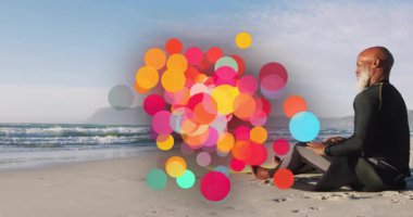 Okyanus kıyısındaki kumlu sahilde oturan kişi üzerinde renkli daireler çiziyor. Tatil, dinlenme, rahatlama, sükunet, sahil şeridi, açık hava.