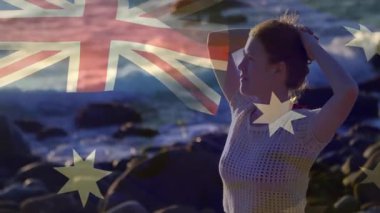 Kayalık sahilde, arka planda Avustralya bayrağı animasyonu olan bir kadın. Vatanseverlik, kıyı şeridi, kutlama, milliyet, gurur, açık hava