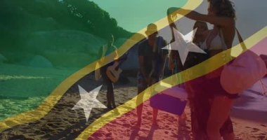 Plajda, insanlar St. Kitts ve Nevis bayrağı kaplamalarıyla rahatlıyorlar. Tatil, rahatlama, Karayipler, turizm, seyahat, tropikal