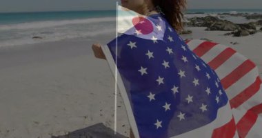 Sahilde duran, yıldız desenli bayrağa sarılmış Japon bayrağı sallayan bir kadın. Vatanseverlik, ulusal gurur, turizm, tatil, seyahat, deniz kenarı