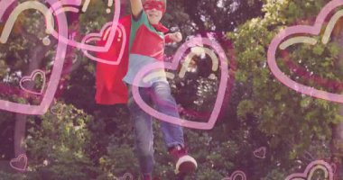 Güneşli arka plan üzerinde kalp animasyonları olan süper kahraman kostümü giyen bir çocuk. Hayal gücü, çocukluk, oyun zamanı, yaratıcılık