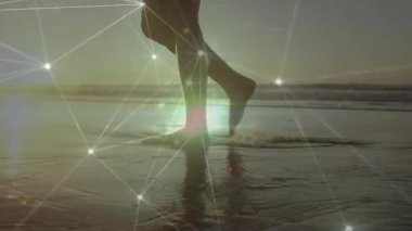 Parlak ağ bağlantılarıyla sahilde yürüyen çıplak ayaklar animasyon örtüsüdür. Teknoloji, yenilik, fütüristik, bağlantı, seyahat, dijital