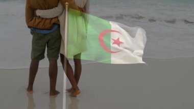 Sahilde kucaklaşan Cezayir bayrağı sallayan bir çift. Romantizm, vatanseverlik, ulusal gurur, aşk, kutlama, deniz kenarı