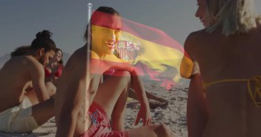 Sahilde dinlenen, arka planda İspanyol bayrağı animasyonu olan gençler. Tatil, tatil, seyahat, okyanus, çok kültürlü, gençlik
