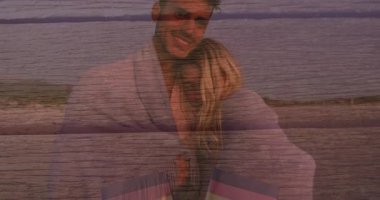 Sahilde kucaklaşan, ahşap desenli arka planda bayrakları olan çift. Romantizm, seyahat, özgürlük, yaşam tarzı, tatil, birlik