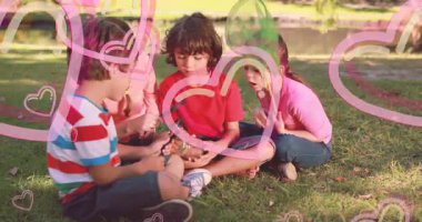 Çimenlerde oturan çocuklar kalp animasyonlarıyla nesneleri inceliyorlar. Açık hava, keşif, doğa, keşif, arkadaşlık, hayal gücü.