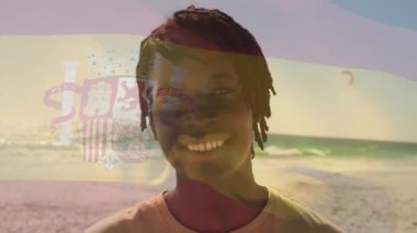 Sahilde, elinde İspanyol bayrağı olan, arka planda animasyonla gülümseyen biri. Vatanseverlik, kutlama, duygu, sahil, tatil, mutluluk