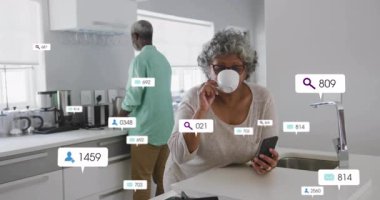 Mutfakta akıllı telefon kullanan yaşlı bir kadın animasyon uyarılarıyla etkileşime geçiyor. Teknoloji, yaşlılar bakımı, iletişim, bağlantı, animasyonlar, aygıtlar
