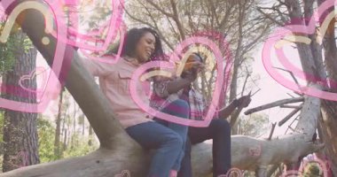 Pembe kalp animasyonu olan bir çift ağaç dalında oturuyor. Romantizm, aşk, ilişki, açık hava, doğa