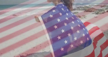 Sahilde yürüyen, bayrak renkleriyle Amerikan bayrağına sarılmış bir kadın. Vatanseverlik, bağımsızlık, ABD, özgürlük, kumlar, kutlama