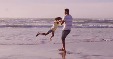 Babası kızı dalgaların üzerinde renkli bir animasyonla sahilde döndürüyor. Aile, neşeli, bağlanan, tatil, neşeli, hareketli