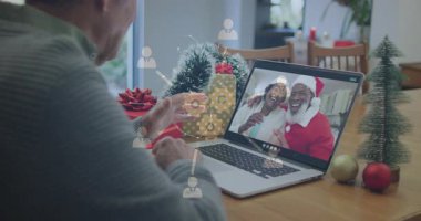 Noel Baba şapkalı bir çift, dijital simgeli animasyon kullanan bir adam. Teknoloji, iletişim, kutlama, festival, sanal, tatil sezonu