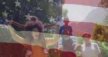 Amerikan bayrağı taşıyan aile dışarıda mutlu vakit geçirip, gülümsüyor ve kaynaşıyor. Vatanseverlik, birlik, ulusal, mutluluk, birliktelik, neşe