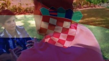 Çimlerin üzerinde oturan, Hırvat bayrağını elinde tutan çocuk açık havada animasyon yapıyordu. Vatanseverlik, çocukluk, doğa, kutlama, miras, ulusal gurur