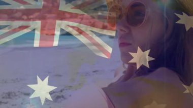 Kumsalda dinlenen, Avustralya bayrağıyla güneşli günün tadını çıkaran bir kadın. Kıyı şeridi, tatil, yaz, seyahat, turizm, tatil